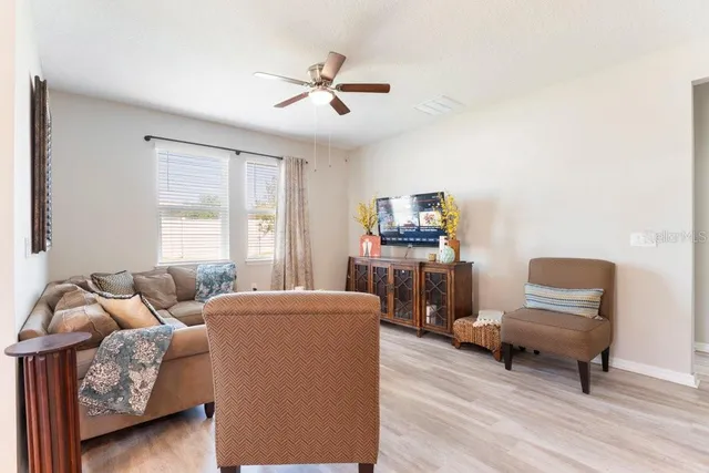 a living room with furniture kitchen view and a wooden floor