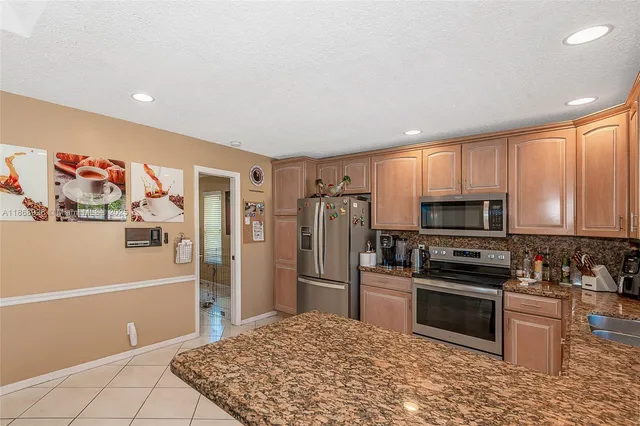 a kitchen with granite countertop a refrigerator and a stove top oven