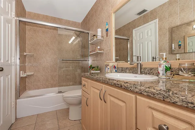 a bathroom with a granite countertop sink a toilet and shower