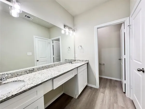 a bathroom with a granite countertop double vanity sink and mirror