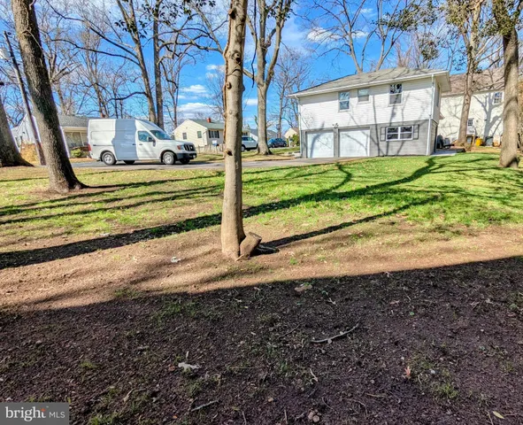 a view of a house with a big yard and large trees