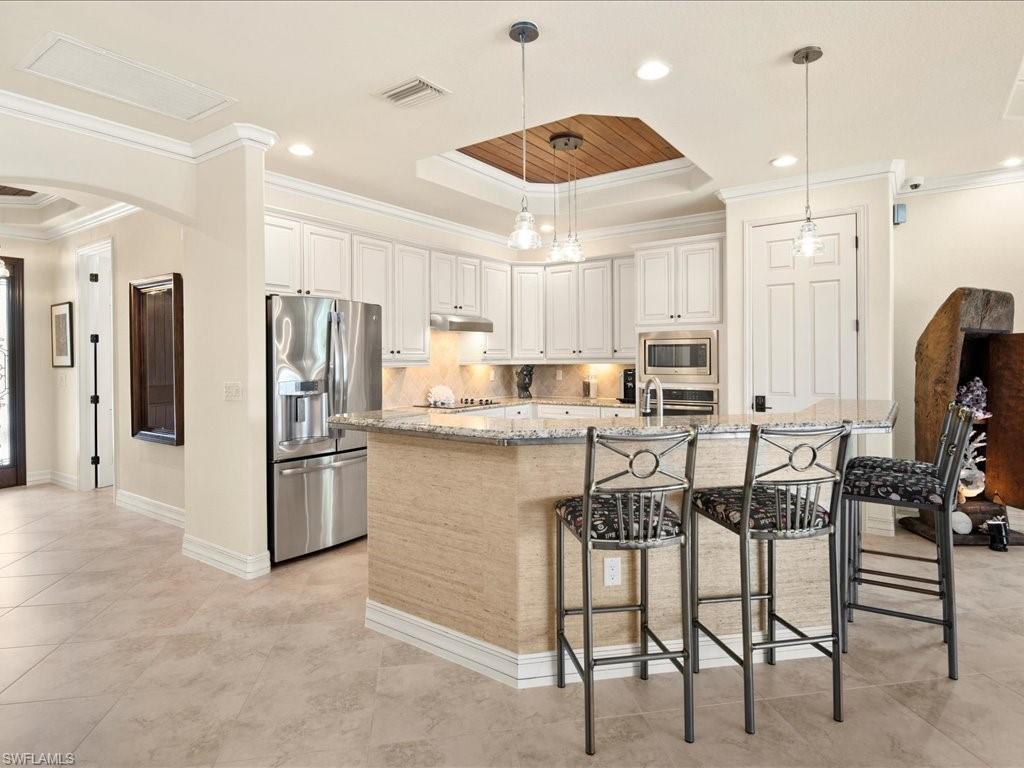 9433 Rialto Drive Naples, FL 34113 - Photo 11 of 35 a kitchen with stainless steel appliances kitchen island granite countertop a table chairs refrigerator and microwave