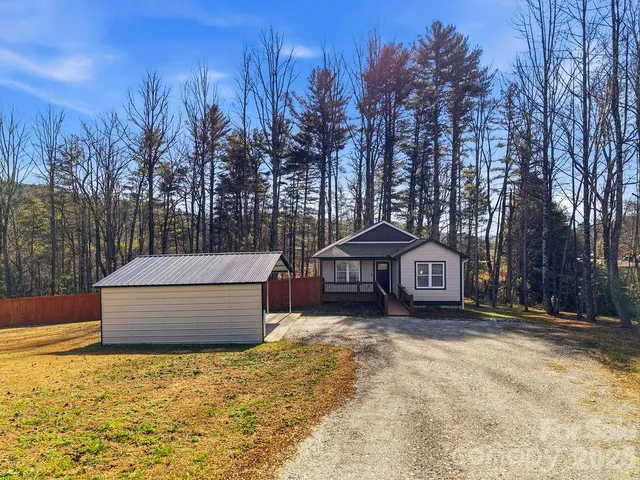 a view of a house with a yard and large trees