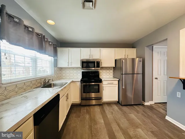 a kitchen with granite countertop a refrigerator stove and sink