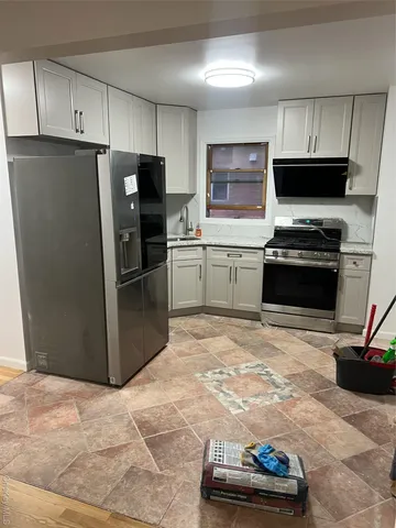 a kitchen with granite countertop a refrigerator and a stove top oven