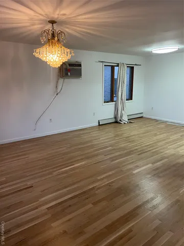 a view of an empty room with window and wooden floor