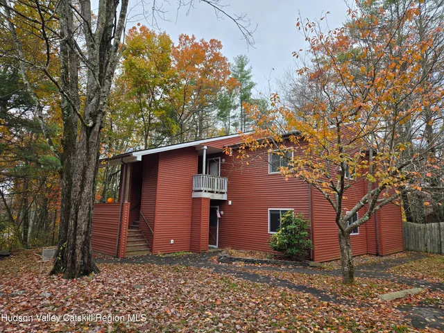 a view of a house with a large tree and wooden fence