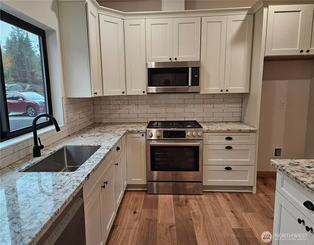 a kitchen with granite countertop a sink and a stove with cabinets
