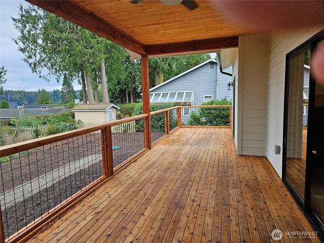 a view of house with wooden deck and floor to ceiling window