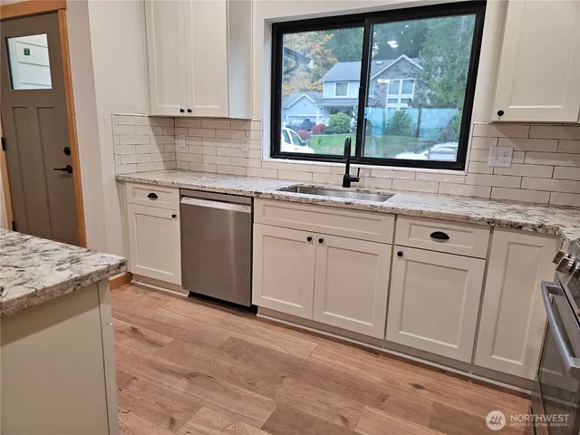 a kitchen with white cabinets and a window