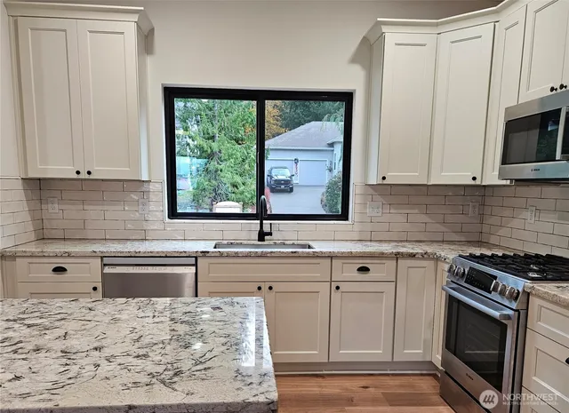 a kitchen with stainless steel appliances granite countertop a stove a sink and a microwave