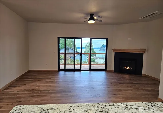 a view of an empty room with wooden floor a fireplace and a window