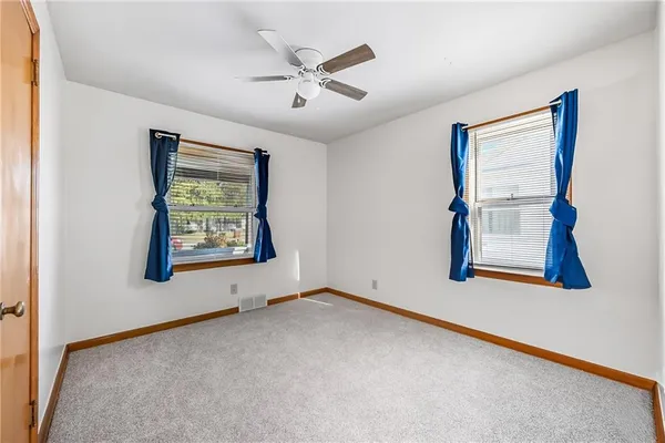 an empty room with window and ceiling fan