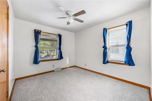 an empty room with window and ceiling fan