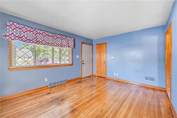 a view of an empty room with window and wooden floor