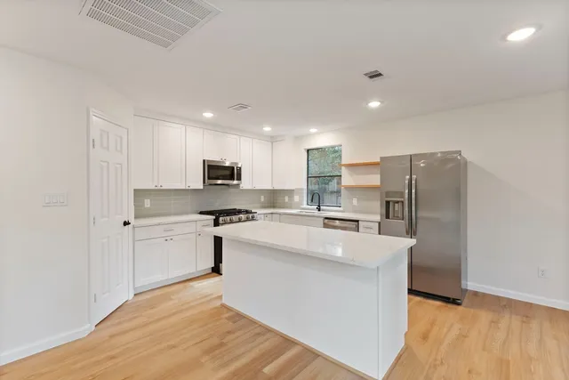 a large kitchen with stainless steel appliances kitchen island a sink a stove a refrigerator and cabinets