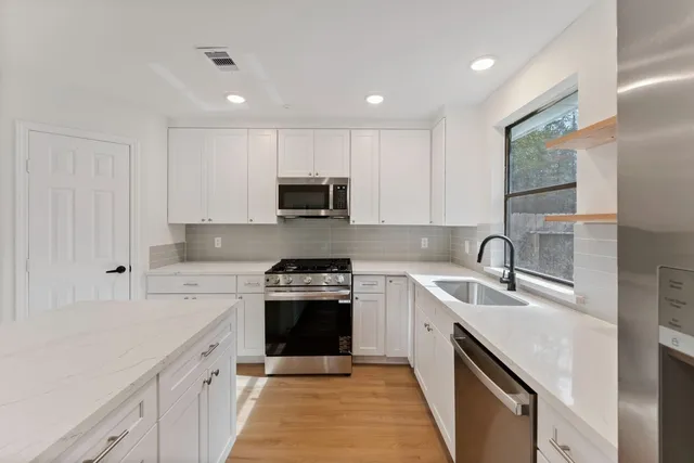 a kitchen with stainless steel appliances granite countertop a sink stove and cabinets