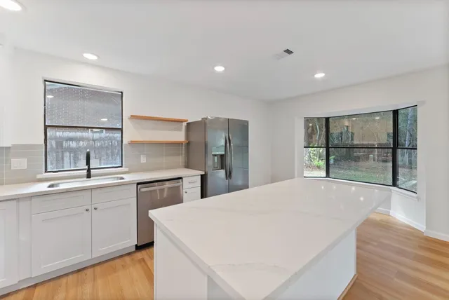 a large white kitchen with a sink and dishwasher a refrigerator with wooden floor