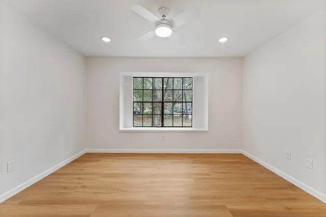 an empty room with wooden floor and windows