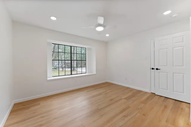 an empty room with wooden floor and windows