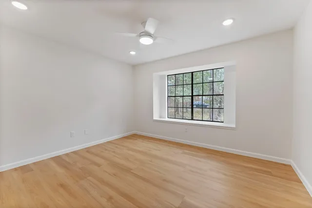 an empty room with wooden floor and windows