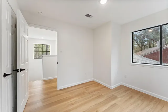 an empty room with wooden floor and windows