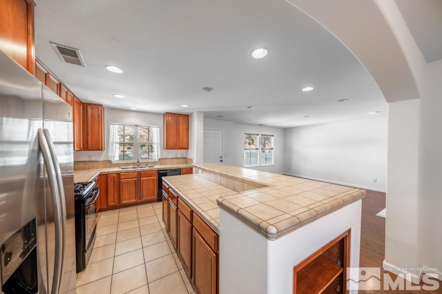 1680 Spicewood Circle Reno, NV 89523 - Photo 15 of 39 a open kitchen with stainless steel appliances granite countertop a refrigerator a sink a stove and island