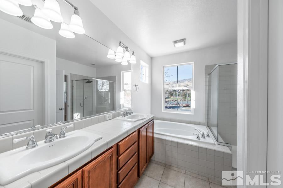 1680 Spicewood Circle Reno, NV 89523 - Photo 26 of 39 a bathroom with a granite countertop sink a large mirror and a bathtub with shower