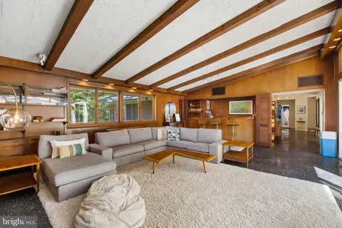 a living room with furniture floor to ceiling windows and wooden floor