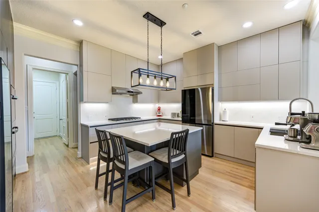 a kitchen with stainless steel appliances a dining table chairs stove refrigerator and cabinets