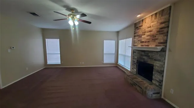 a view of an empty room with chandelier fan and fire place