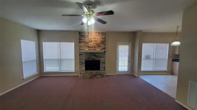 an empty room with windows and fireplace