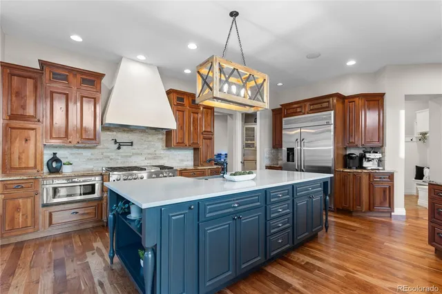a kitchen with a stove a sink a center island and wooden floor