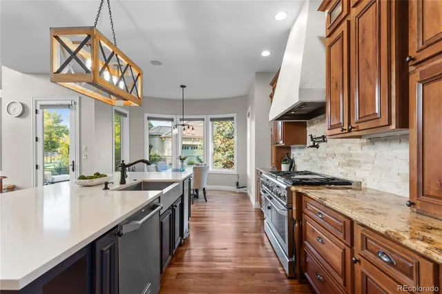 a kitchen with stainless steel appliances granite countertop a sink a stove and a wooden floors