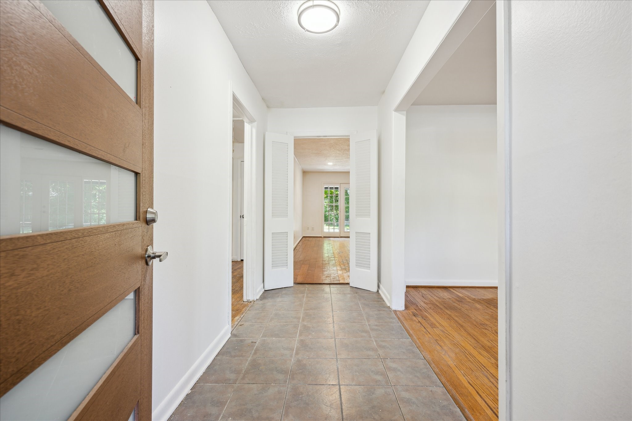 5419 Beechnut Street Houston, TX 77096 - Photo 4 of 28 Bright entryway with tile flooring and clean lines, opening to light-filled living spaces with wood floors and French doors overlooking the backyard.
