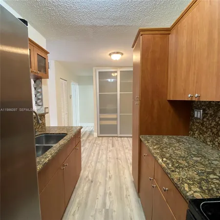 a kitchen with granite countertop a sink and refrigerator