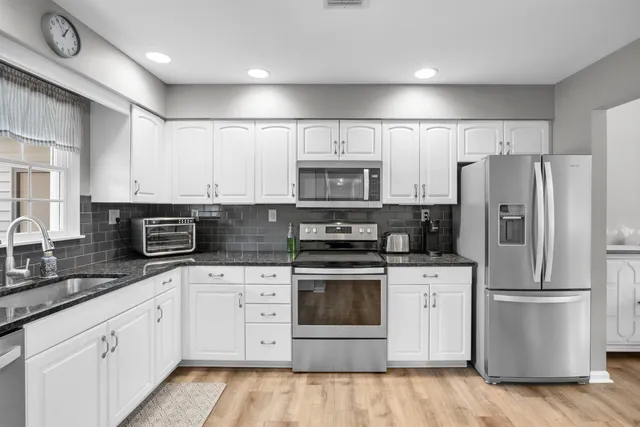 a kitchen with white cabinets white stainless steel appliances and sink