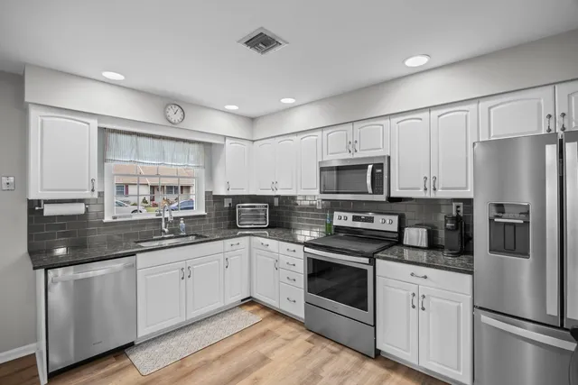 a kitchen with a sink stainless steel appliances and white cabinets