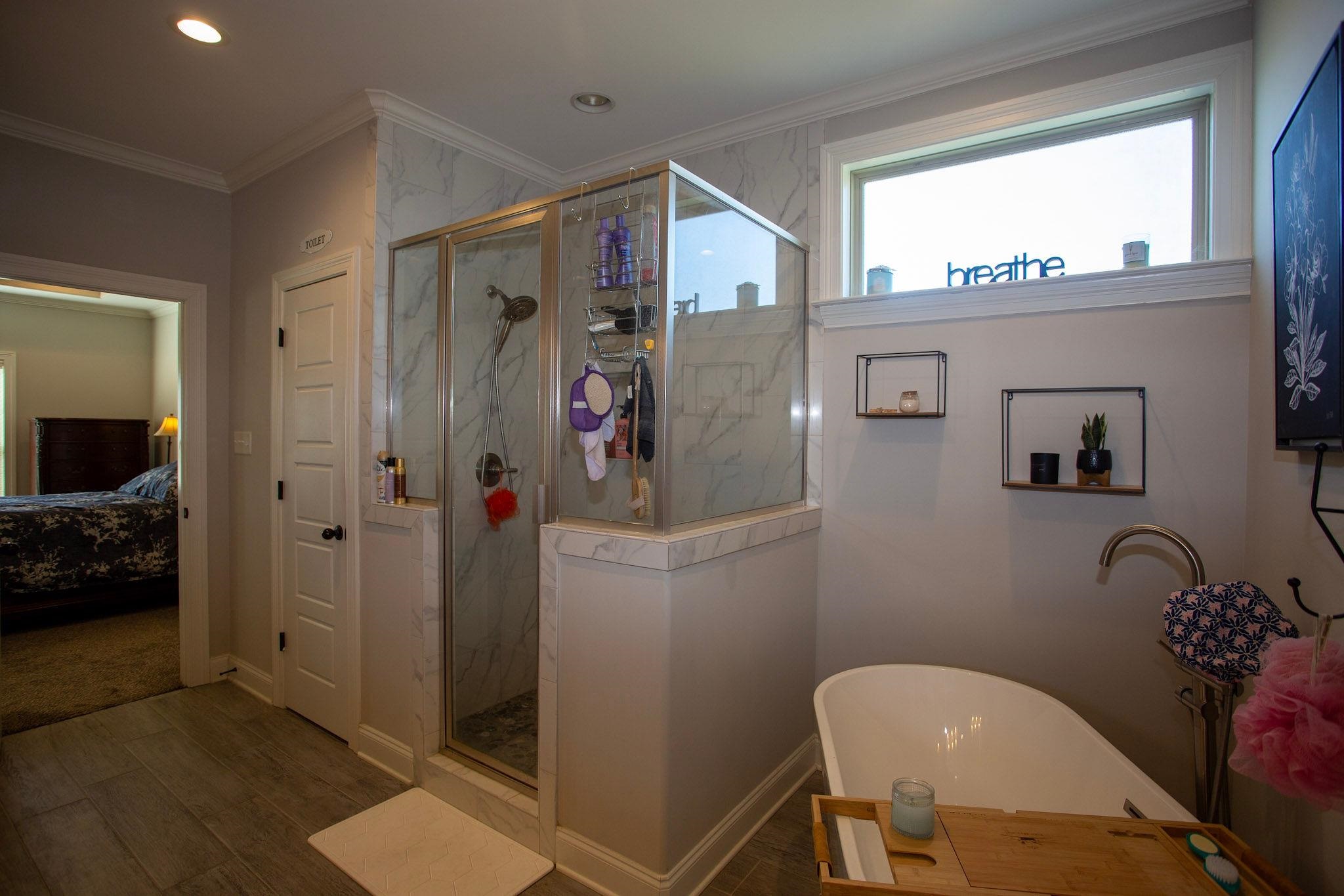 22 Cedar Ridge Cove Atoka, TN 38004 - Photo 24 of 39 Bathroom featuring crown molding, wood-type flooring, and separate shower and tub