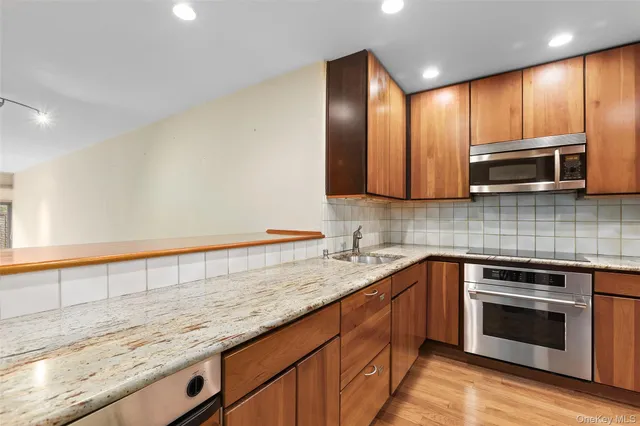 a kitchen with stainless steel appliances granite countertop wooden cabinets and a stove top oven