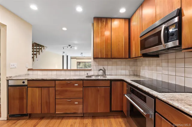 a kitchen with granite countertop wooden cabinets stainless steel appliances and a sink