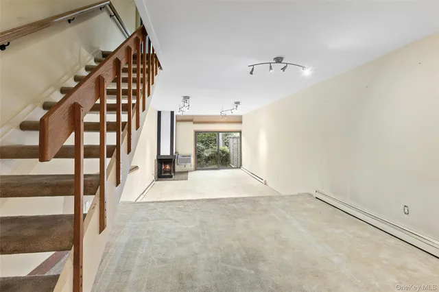 a view of an empty room with staircase and door