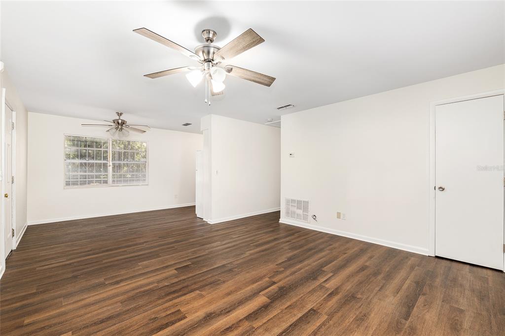 2511 Northeast 3rd Place Gainesville, FL 32641 - Photo 4 of 29 an empty room with wooden floor chandelier fan and windows