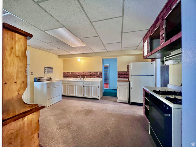 479 East 100 N Road Meadow, UT 84644 - Photo 14 of 59 Kitchen with white appliances, washer / clothes dryer, a paneled ceiling, light countertops, and concrete floors