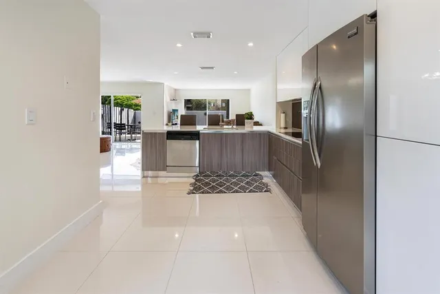 a kitchen with stainless steel appliances kitchen island granite countertop a refrigerator a stove and a sink with large countertops