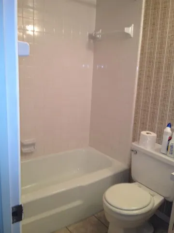 a white toilet sitting next to a bath tub