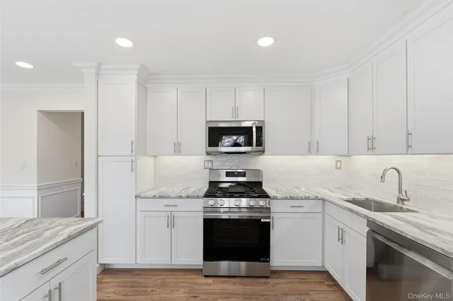 a kitchen with granite countertop white cabinets and stainless steel appliances