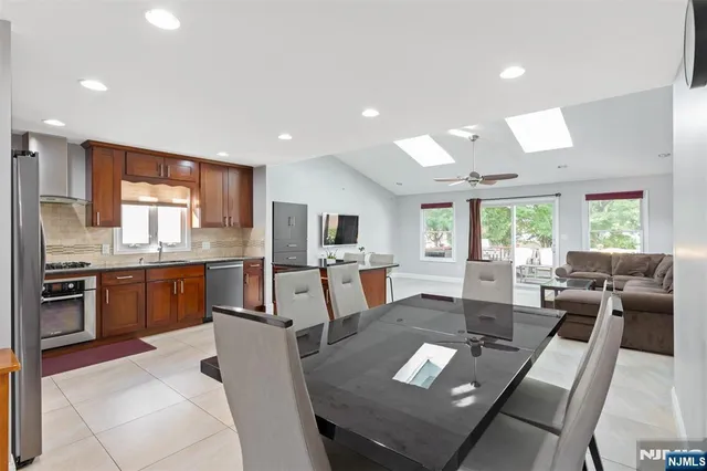 a living room with stainless steel appliances furniture a dining table and kitchen view