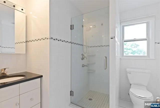 a bathroom with a granite countertop sink a toilet and shower