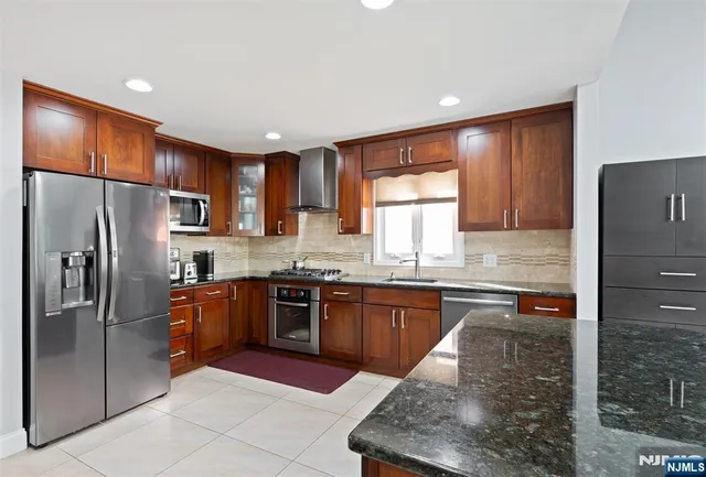 a kitchen with stainless steel appliances granite countertop a refrigerator sink and stove